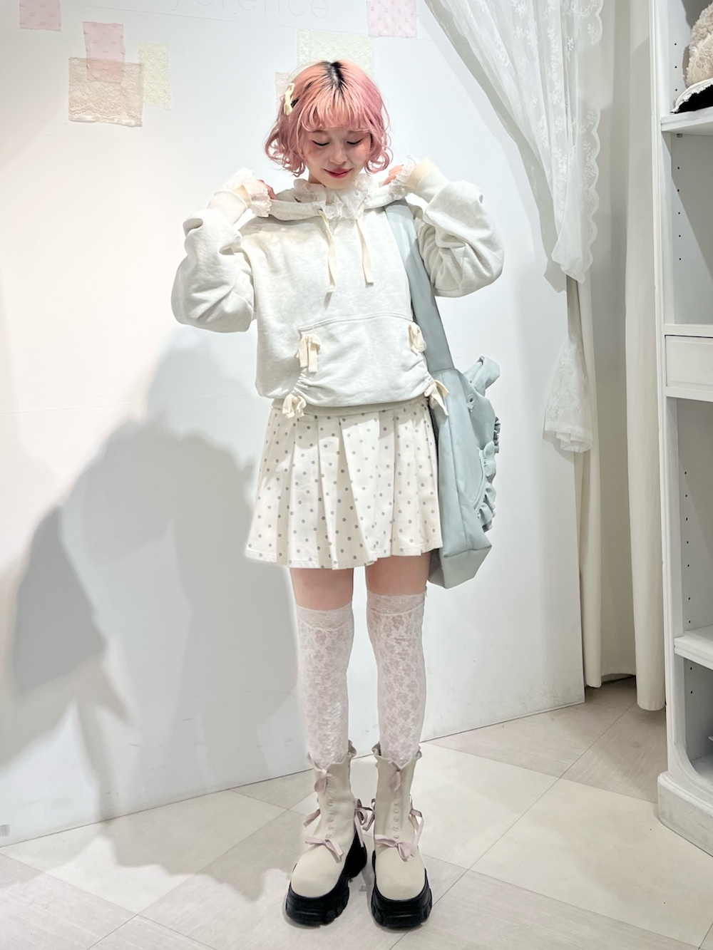 グレー系のパーカー、ホワイト系のスカート、ブルー系のショルダーバッグを着用したレディースの秋コーディネートの2枚目の写真