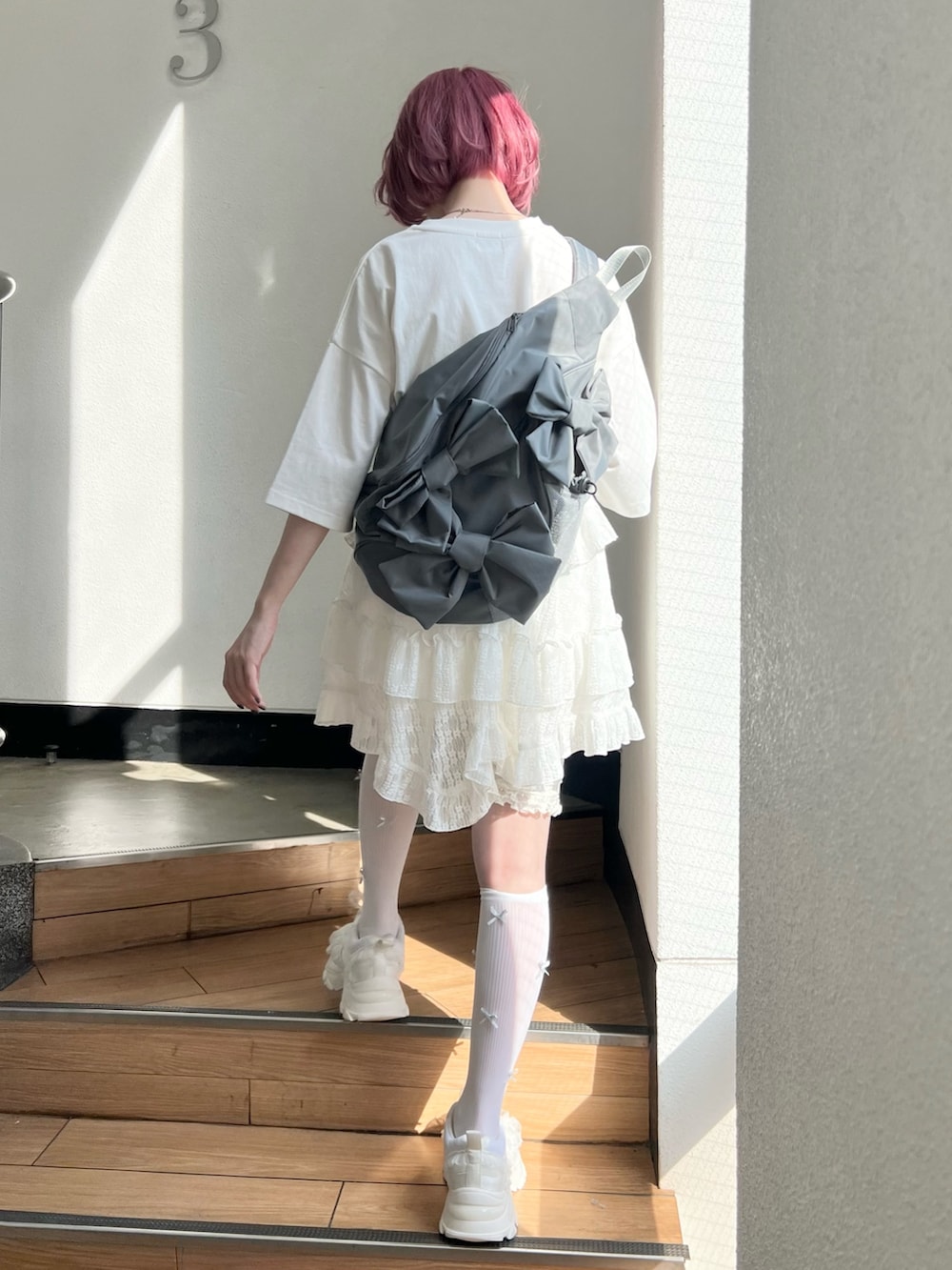 ホワイト系のTシャツ/カットソー、ホワイト系のスカート、ホワイト系のスニーカーを着用したレディースの春コーディネートの4枚目の写真