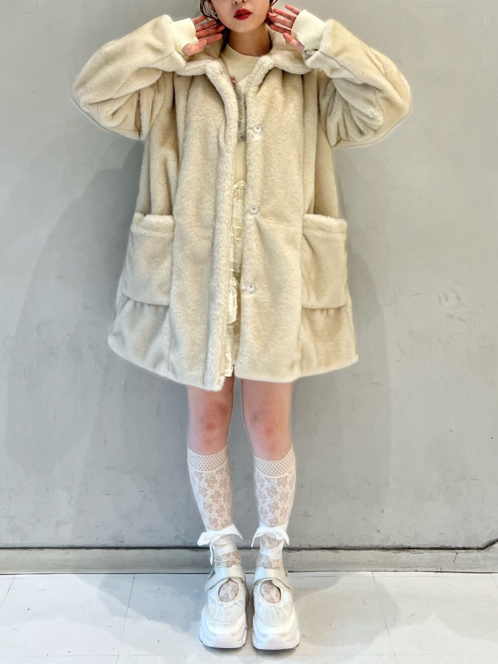 ホワイト系のノーカラーコート、ホワイト系のスカート、ホワイト系のニット/セーターを着用したレディースの冬コーディネートの2枚目の写真