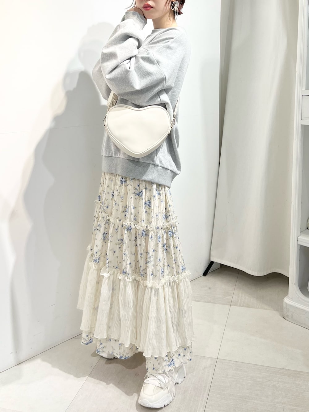 ホワイト系のショルダーバッグ、ホワイト系のスニーカー、ブルー系のスカートを着用したレディースの冬コーディネートの2枚目の写真