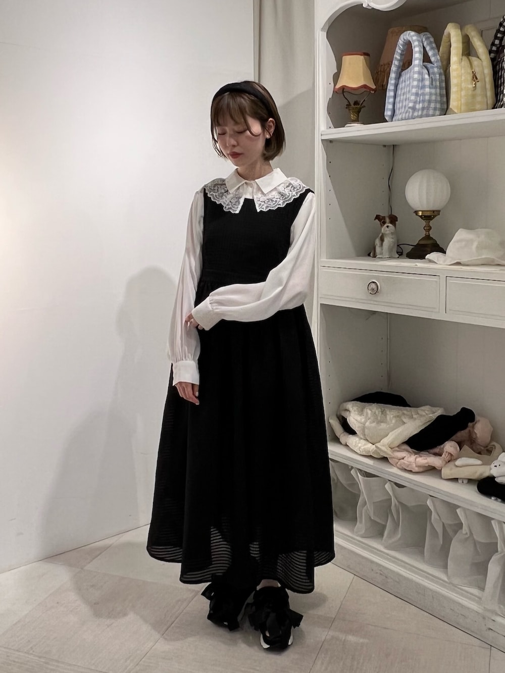 ホワイト系のチュニック、ブラック系のサンダル、ブラック系のワンピースを着用したレディースの春コーディネートの3枚目の写真