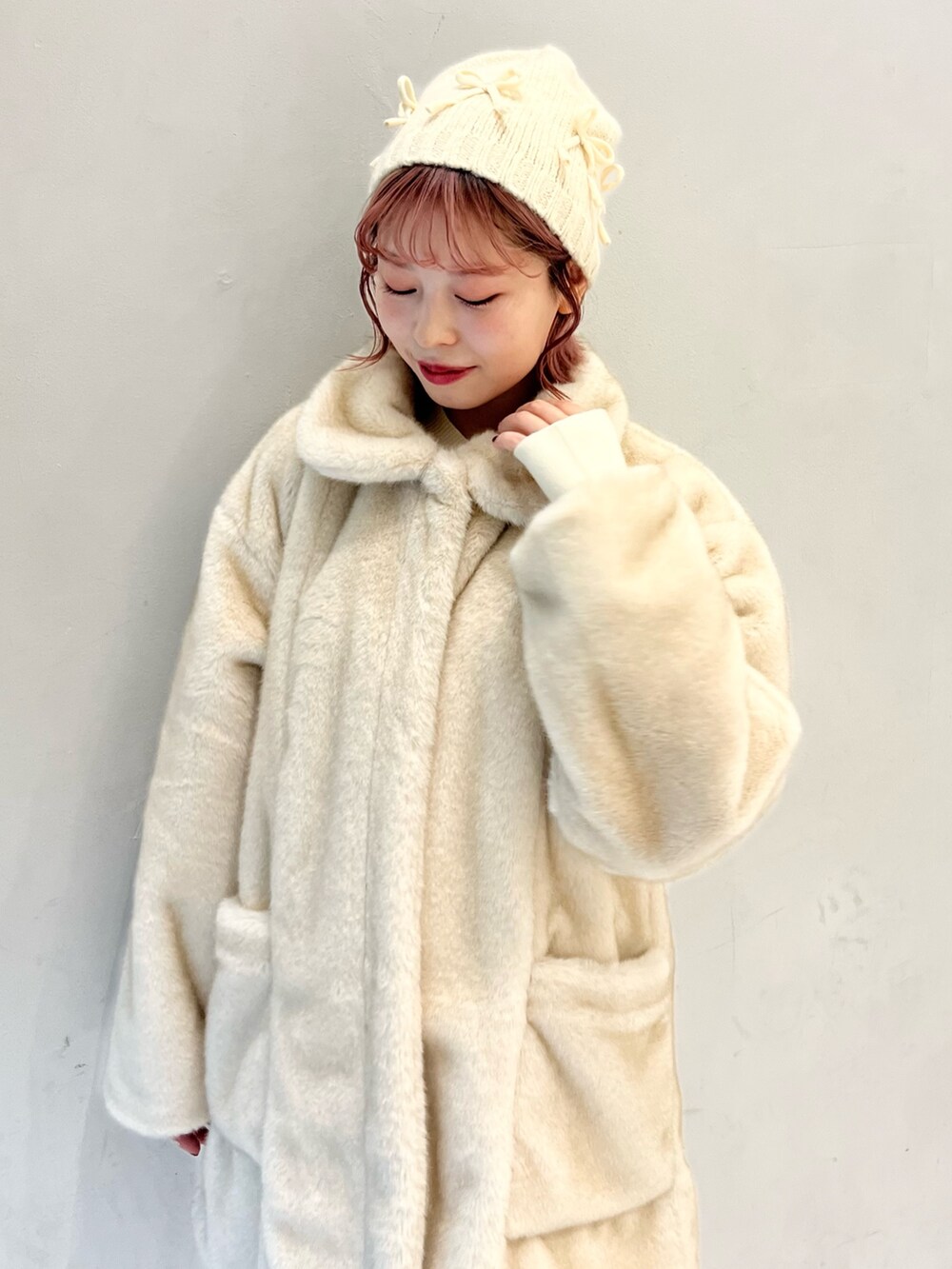 ホワイト系のノーカラーコート、ホワイト系のスカート、ホワイト系のニット/セーターを着用したレディースの冬コーディネートの7枚目の写真