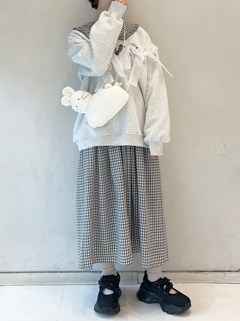 ブラック系のワンピース、ブラック系のスニーカー、ホワイト系のショルダーバッグを着用したレディースの冬コーディネートの4枚目の写真