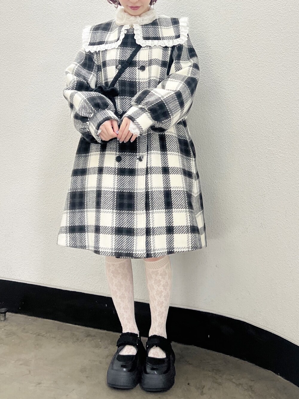 ブラック系のチェスターコート、ホワイト系のニット/セーター、ブラック系のハンドバッグを着用したレディースの秋コーディネートの3枚目の写真