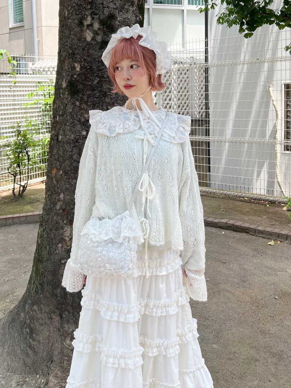 ホワイト系のハンドバッグ、ホワイト系のスカート、ホワイト系のブーツを着用したレディースの夏コーディネートの6枚目の写真