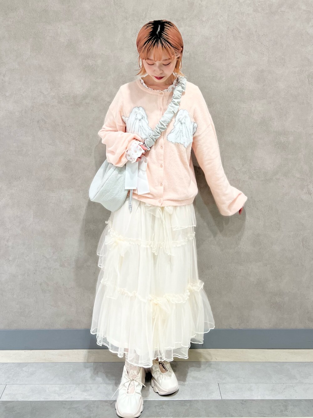 ピンク系のTシャツ/カットソー、ホワイト系のスカート、ホワイト系のスニーカーを着用したレディースの秋コーディネートの4枚目の写真