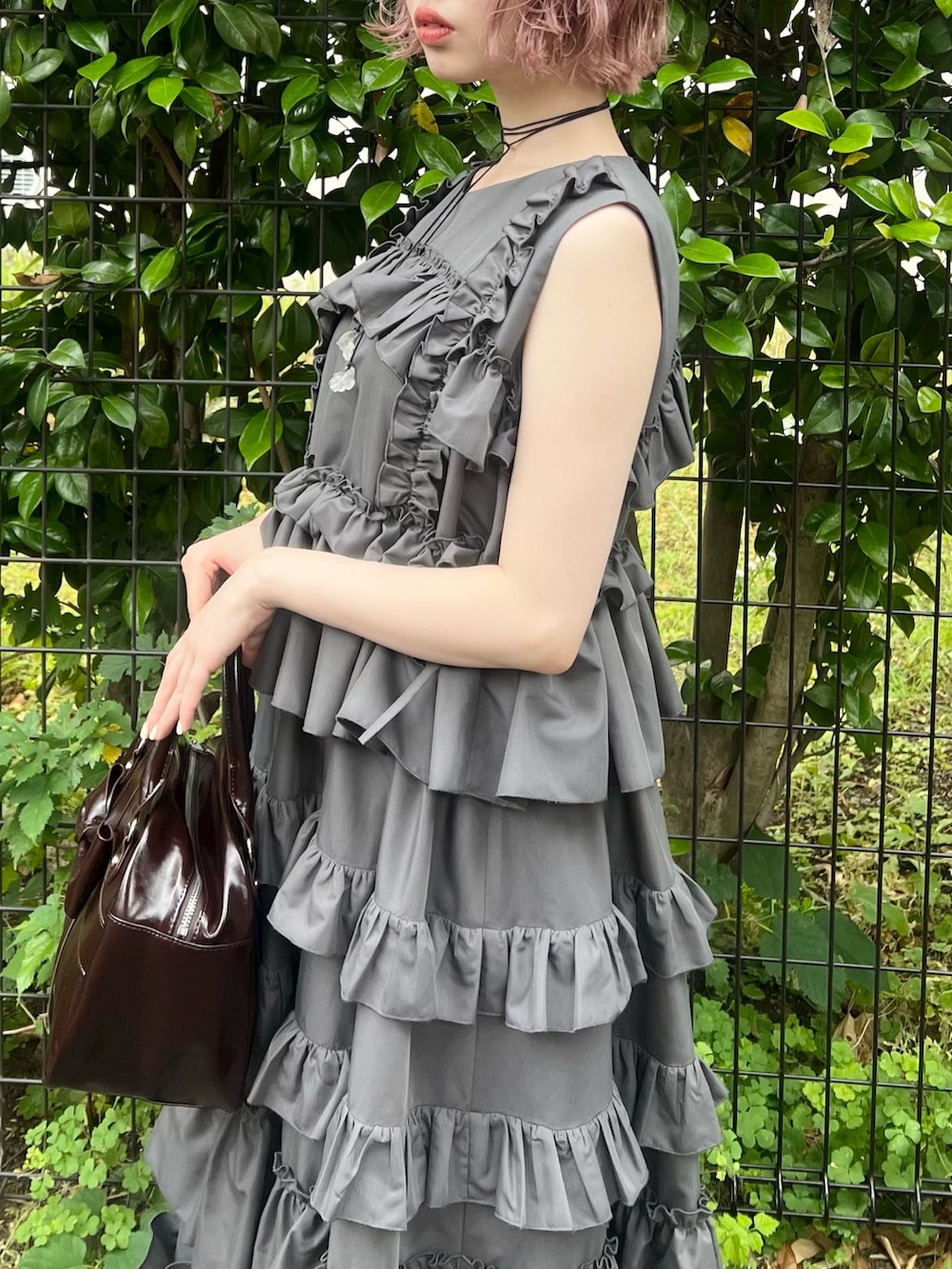 グレー系のワンピース、ブラウン系のハンドバッグ、ブラック系のブーツを着用したレディースの夏コーディネートの6枚目の写真