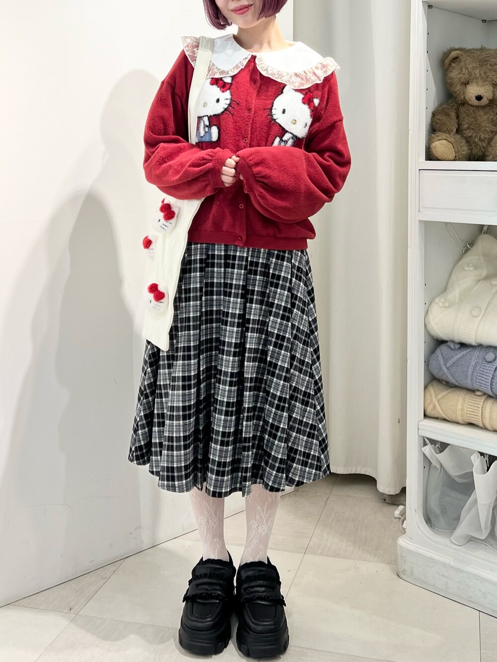 レッド系のカーディガン/ボレロ、ゴールド系のシャツ/ブラウス、ブラック系のスカートを着用したレディースの秋コーディネートの3枚目の写真