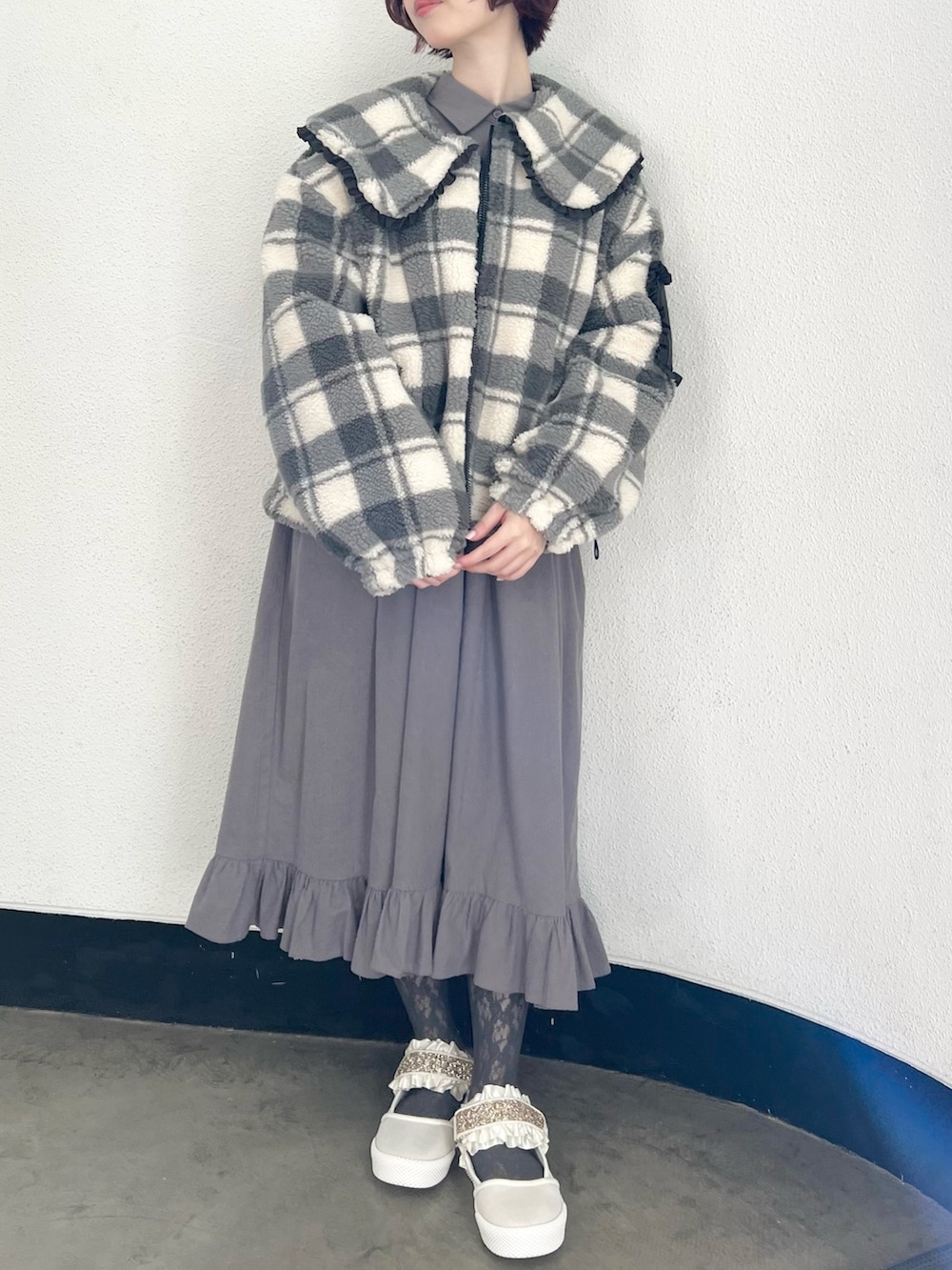 ブラック系のブルゾン、グレー系のワンピース、ホワイト系のスニーカーを着用したレディースの冬コーディネートの3枚目の写真