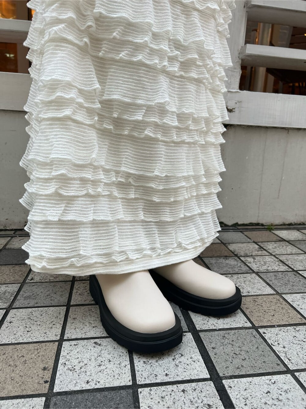 イエロー系のマウンテンパーカー、ホワイト系のブーツ、ホワイト系のワンピースを着用したレディースの秋コーディネートの8枚目の写真