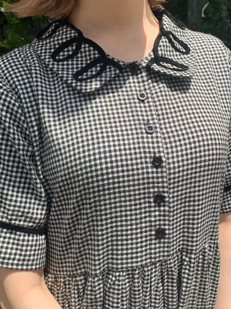 ブラック系のスニーカー、ブラック系のワンピース、ホワイト系のハンドバッグを着用したレディースの夏コーディネートの4枚目の写真