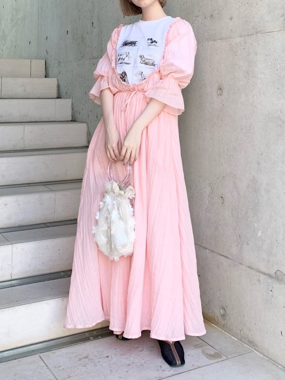 ブラック系のパンプス、ホワイト系のハンドバッグ、ピンク系のワンピースを着用したレディースの春コーディネートの2枚目の写真