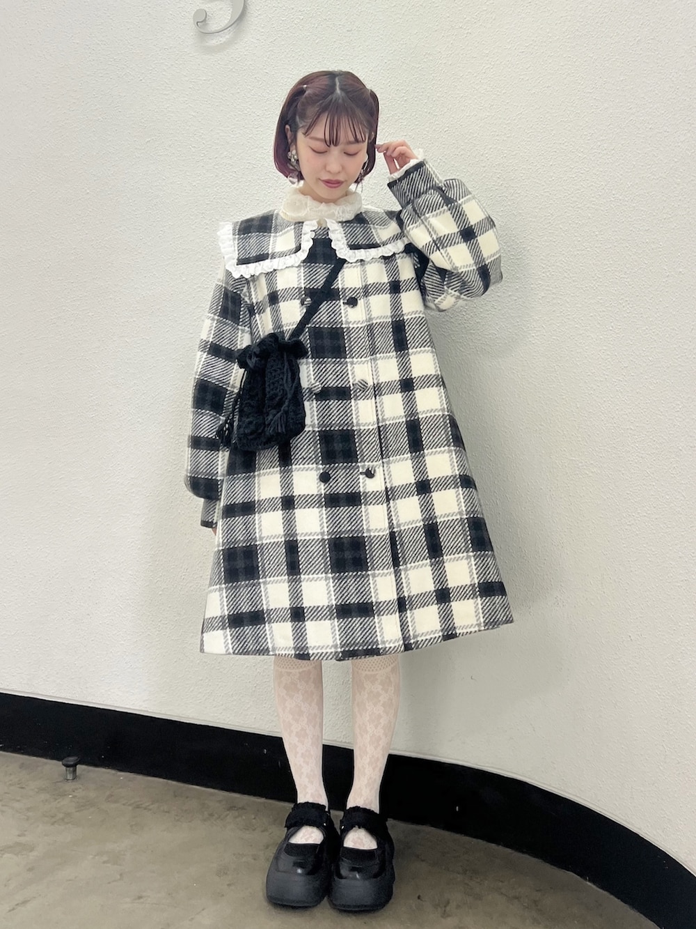 ブラック系のチェスターコート、ホワイト系のニット/セーター、ブラック系のハンドバッグを着用したレディースの秋コーディネートの2枚目の写真