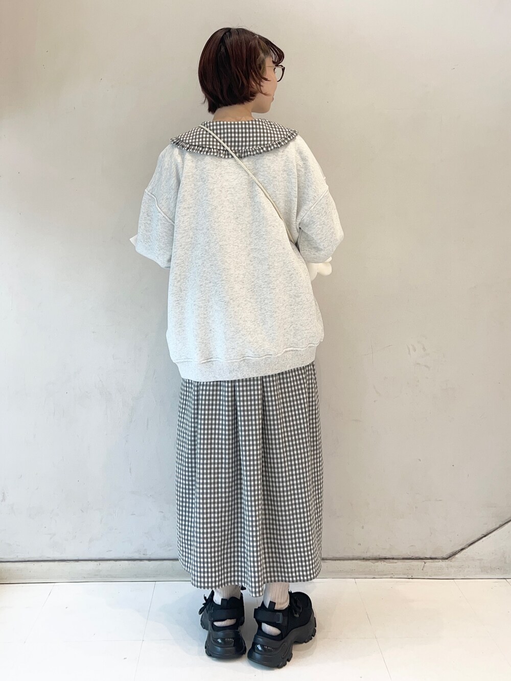 ブラック系のワンピース、ブラック系のスニーカー、ホワイト系のショルダーバッグを着用したレディースの冬コーディネートの6枚目の写真