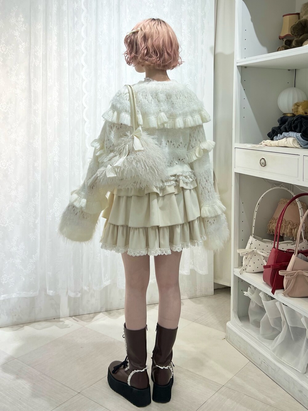 ホワイト系のボストンバッグ、ブラウン系のブーツ、ホワイト系のスカートを着用したレディースの夏コーディネートの6枚目の写真