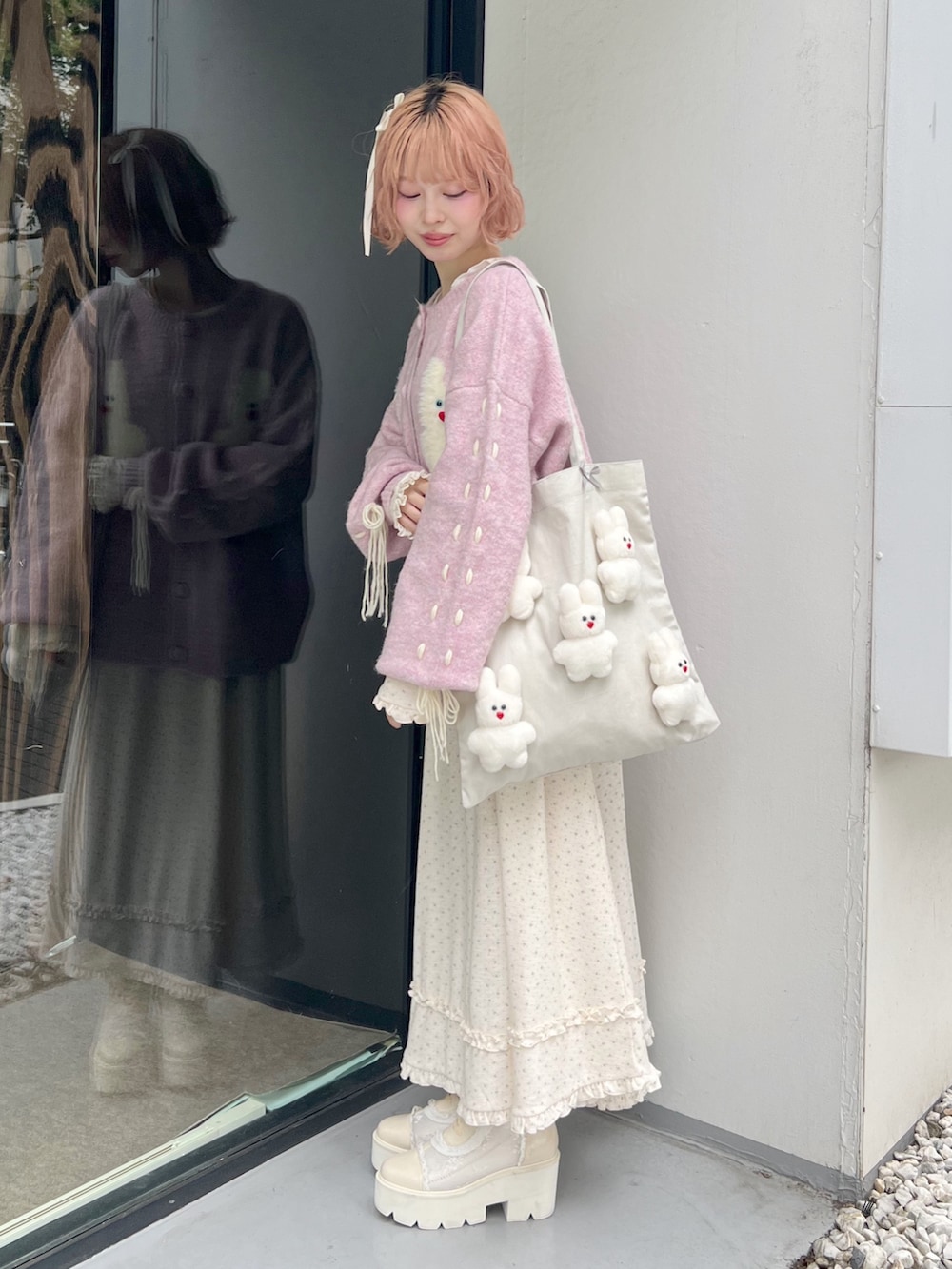 ホワイト系のブーツ、ピンク系のカーディガン/ボレロ、ホワイト系のトートバッグを着用したレディースの秋コーディネートの2枚目の写真