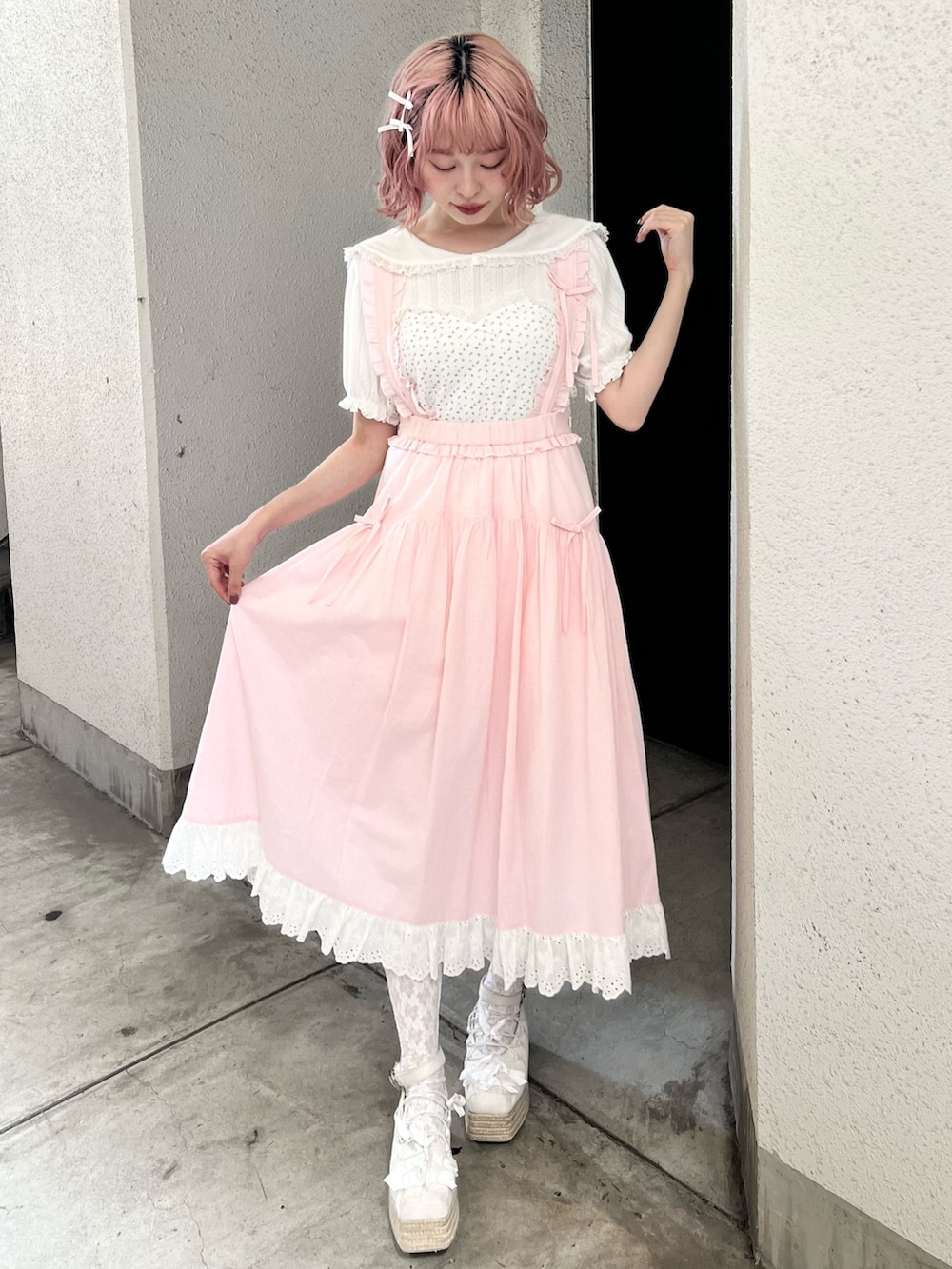 ホワイト系のTシャツ/カットソー、ピンク系のジャンパースカート、ホワイト系のサンダルを着用したレディースの夏コーディネートの2枚目の写真