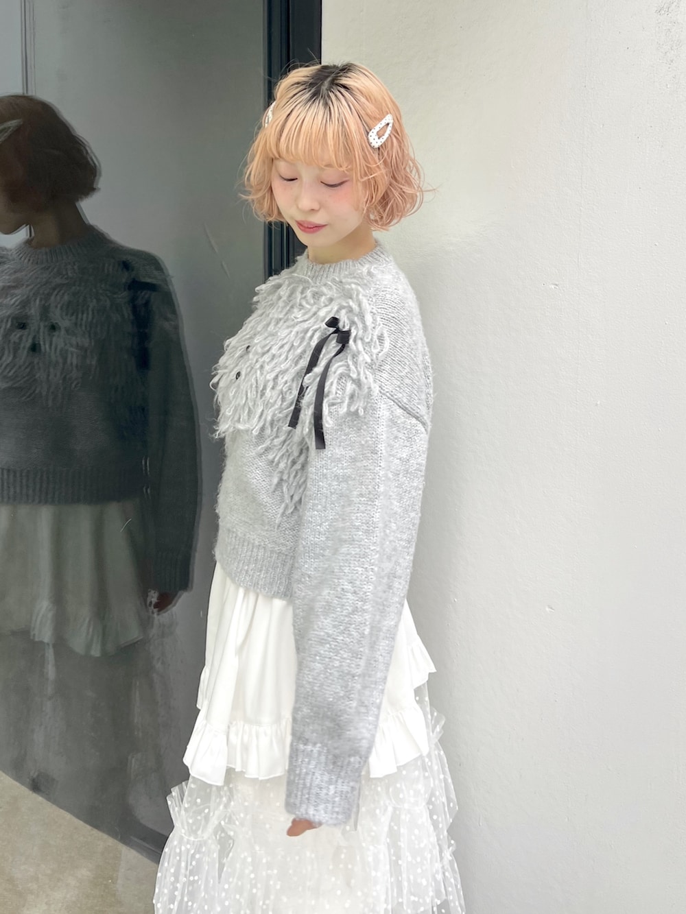 グレー系のニット/セーター、ホワイト系のショルダーバッグ、ホワイト系のスカートを着用したレディースの秋コーディネートの6枚目の写真