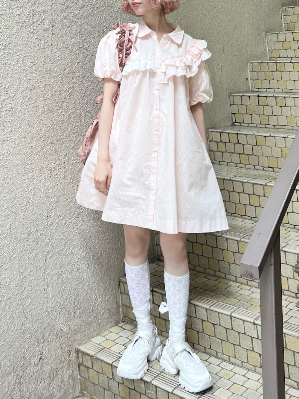 ピンク系のワンピース、ピンク系のトートバッグ、ホワイト系のスニーカーを着用したレディースの春コーディネートの5枚目の写真