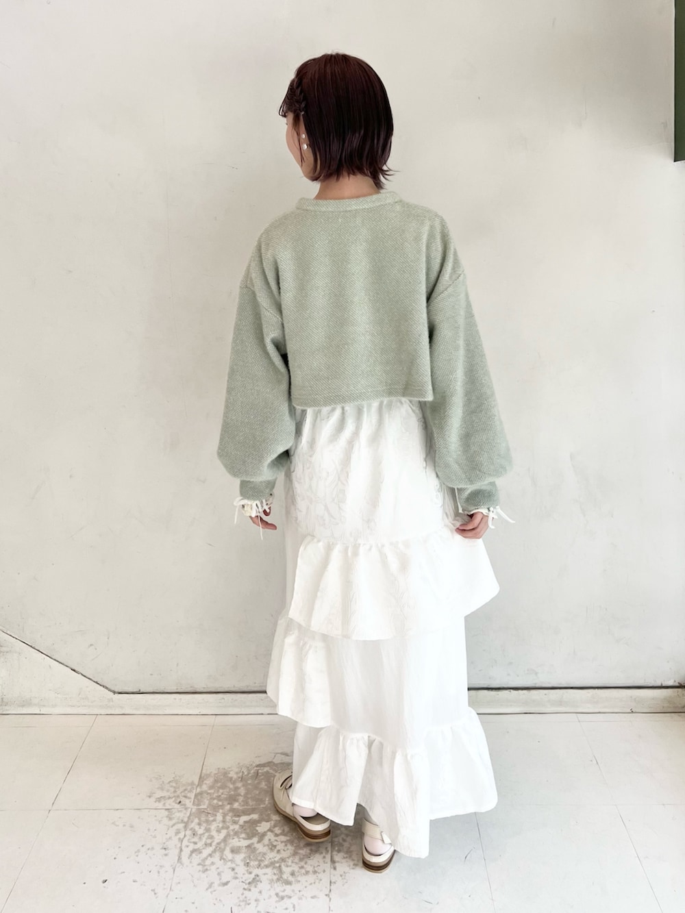 グリーン系のカーディガン/ボレロ、ホワイト系のスカート、ホワイト系のTシャツ/カットソーを着用したレディースの秋コーディネートの4枚目の写真