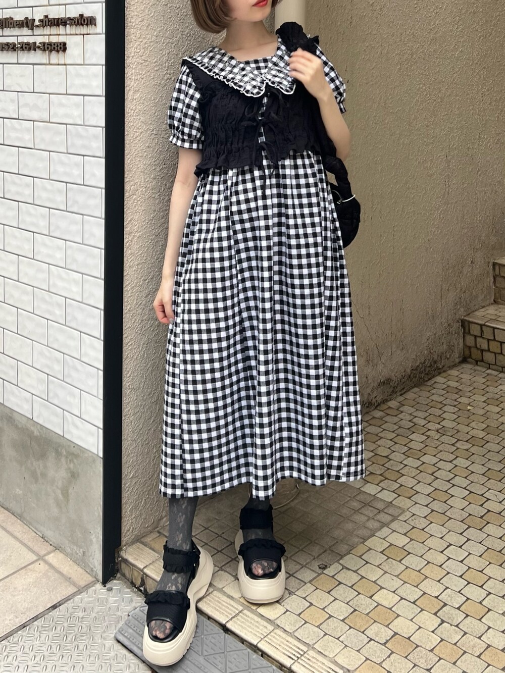 ブラック系のベスト、ブラック系のサンダル、ブラック系のワンピースを着用したレディースの夏コーディネートの5枚目の写真