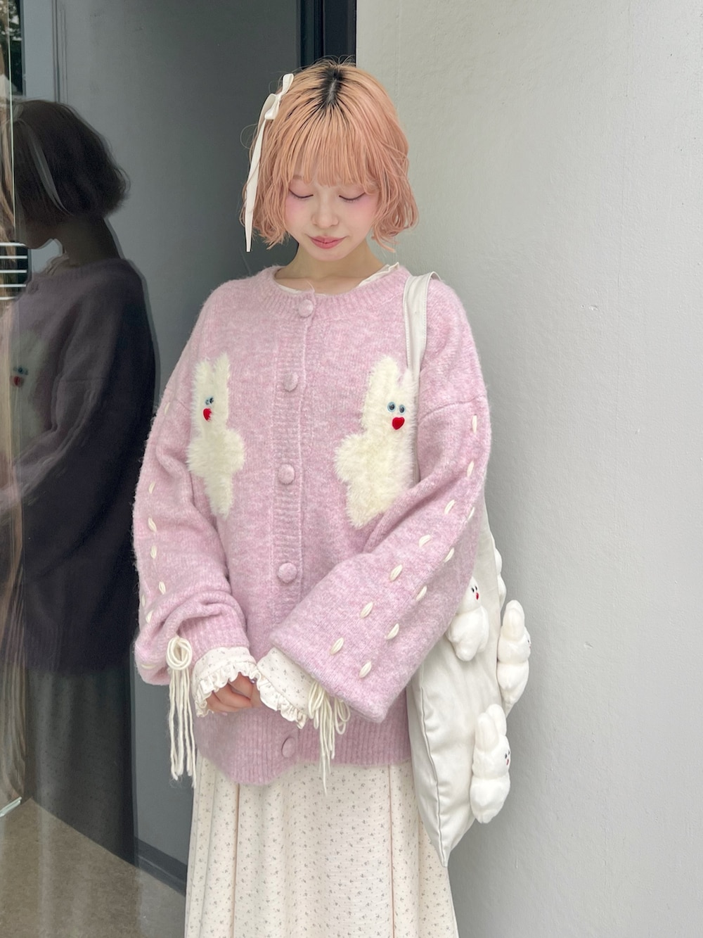 ホワイト系のブーツ、ピンク系のカーディガン/ボレロ、ホワイト系のトートバッグを着用したレディースの秋コーディネートの4枚目の写真