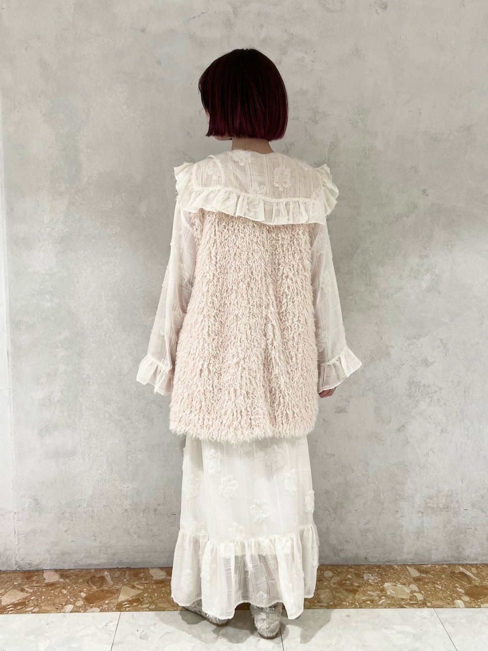 ホワイト系のダウンベスト、グリーン系のパンプス、ホワイト系のワンピースを着用したレディースの冬コーディネートの7枚目の写真