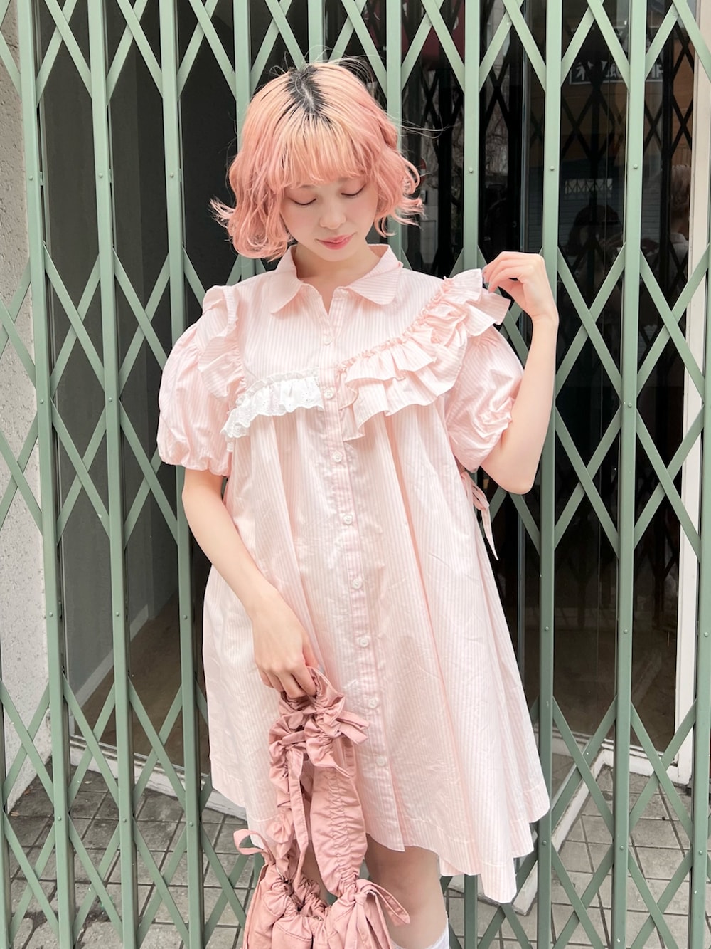 ピンク系のワンピース、ピンク系のトートバッグ、ホワイト系のスニーカーを着用したレディースの春コーディネートの2枚目の写真