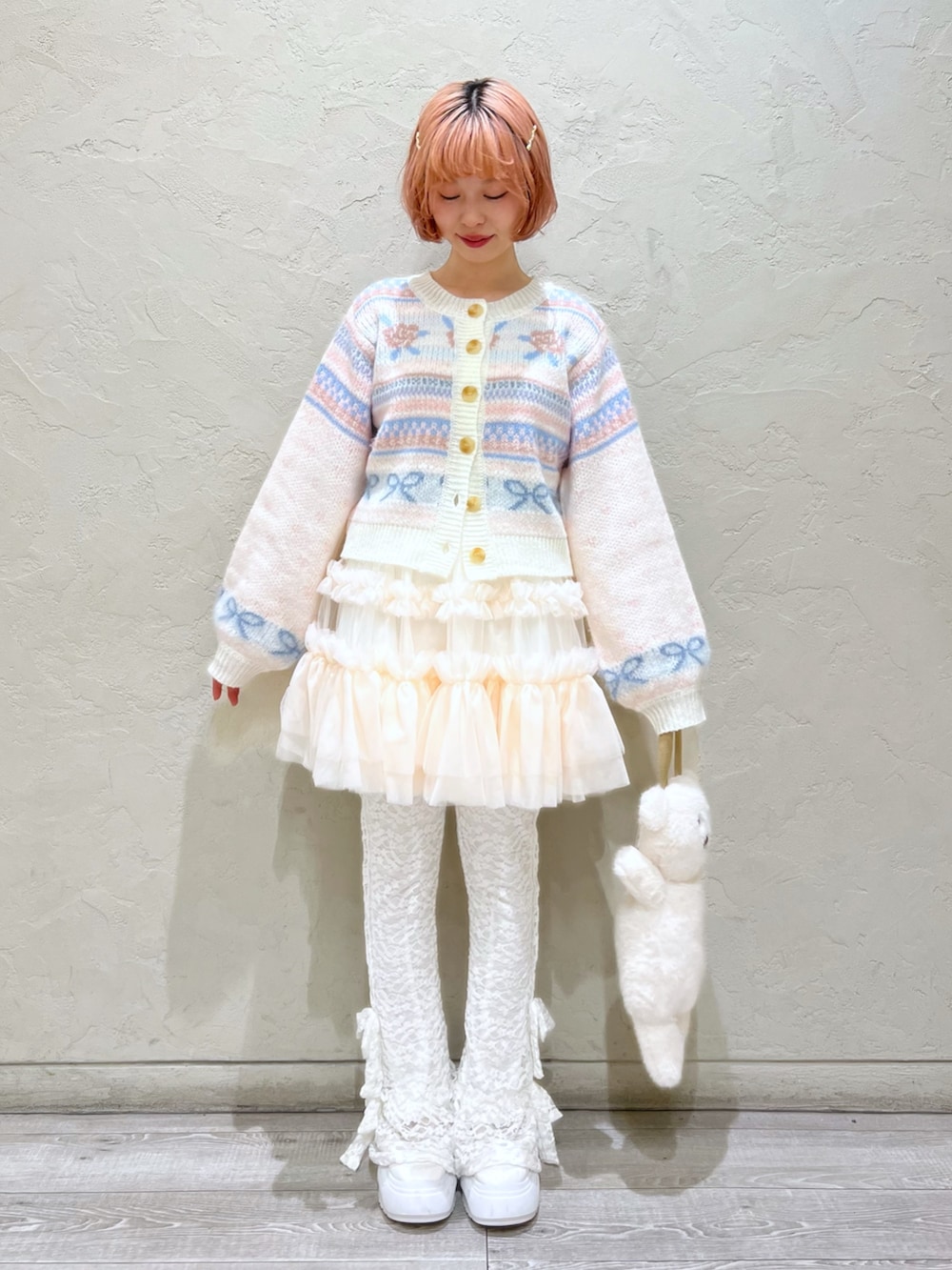 ホワイト系のカーディガン/ボレロ、ピンク系のスカート、ホワイト系のハンドバッグを着用したレディースの秋コーディネートの2枚目の写真