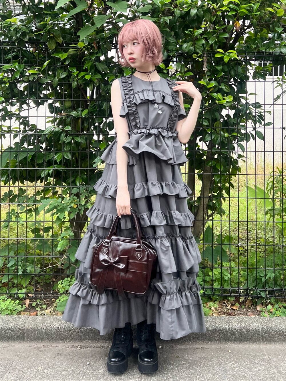グレー系のワンピース、ブラウン系のハンドバッグ、ブラック系のブーツを着用したレディースの夏コーディネートの5枚目の写真