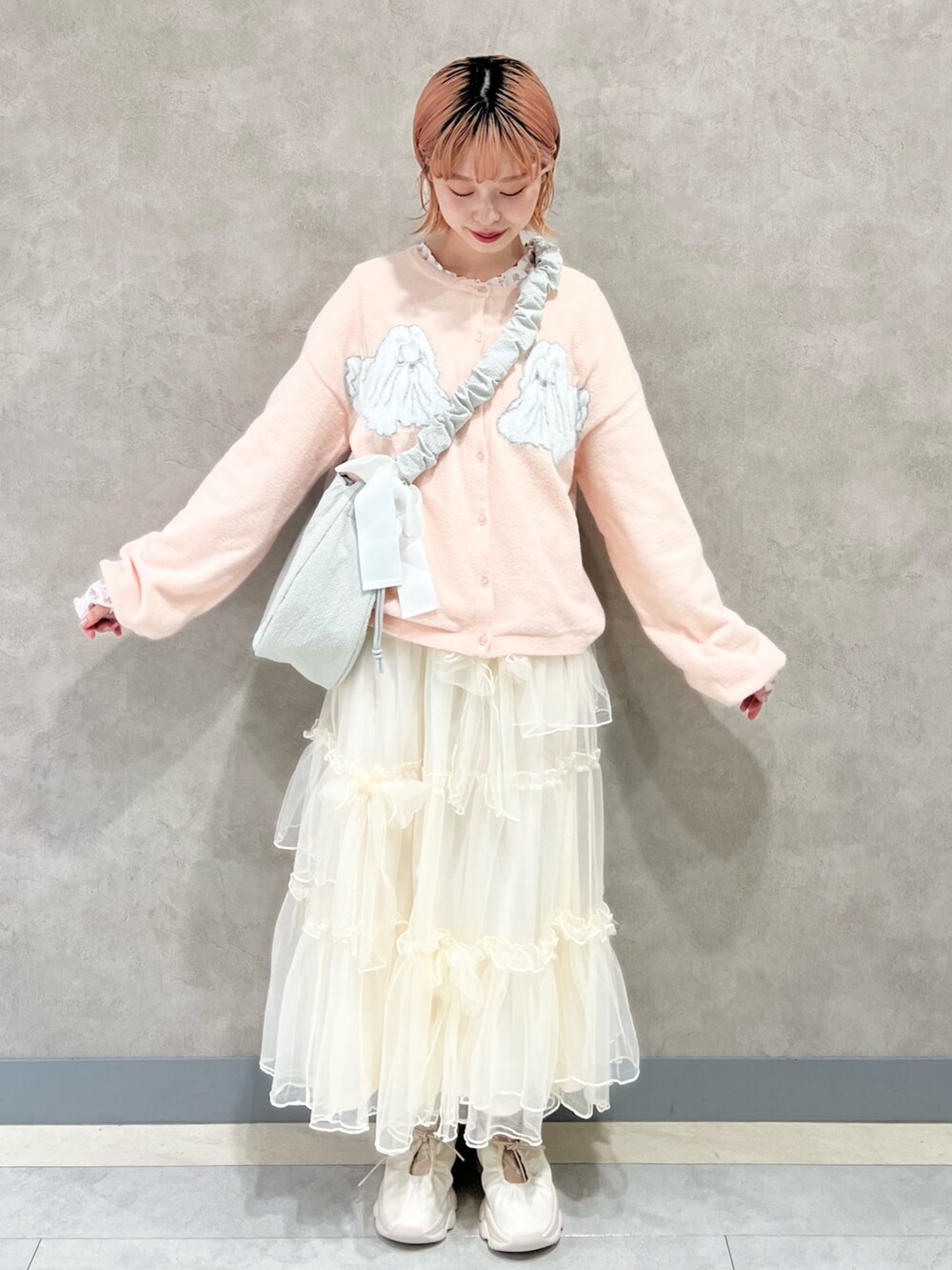 ピンク系のTシャツ/カットソー、ホワイト系のスカート、ホワイト系のスニーカーを着用したレディースの秋コーディネートの3枚目の写真