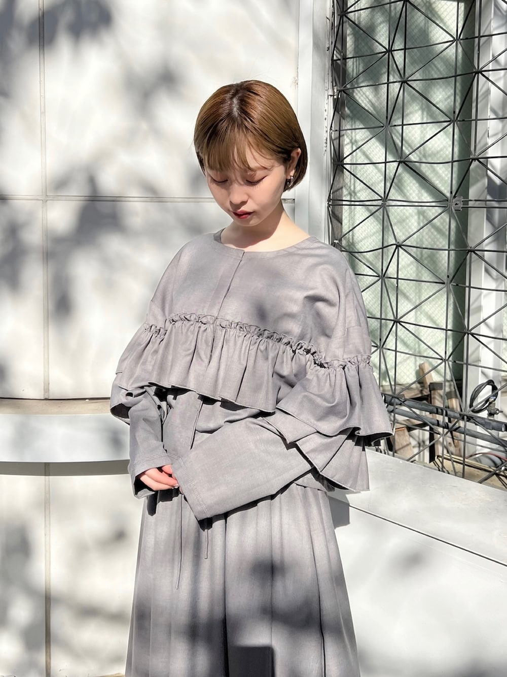 グレー系のテーラードジャケット、グレー系のスカート、ブラック系のパンプスを着用したレディースの秋コーディネートの6枚目の写真