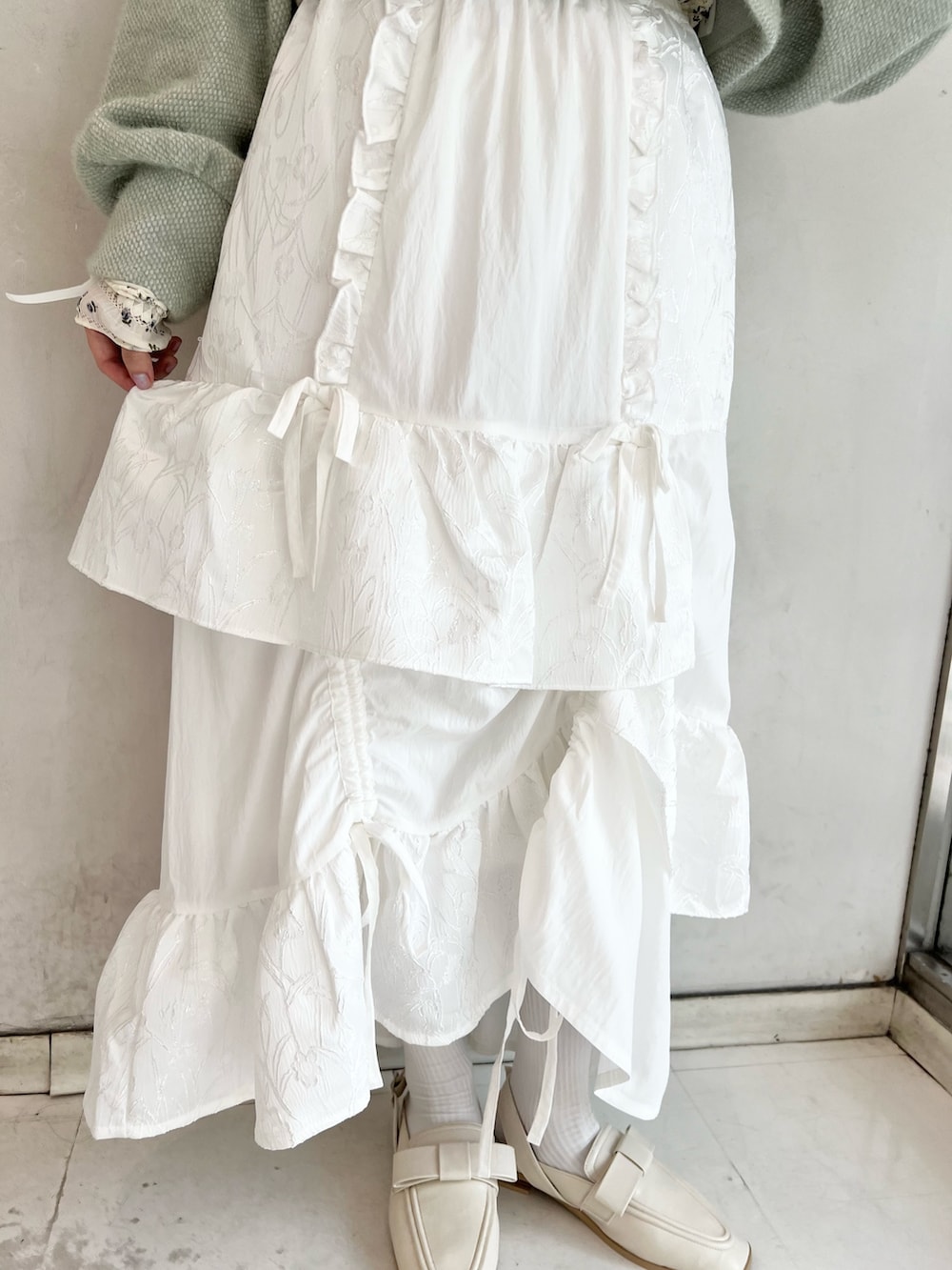 グリーン系のカーディガン/ボレロ、ホワイト系のスカート、ホワイト系のTシャツ/カットソーを着用したレディースの秋コーディネートの9枚目の写真