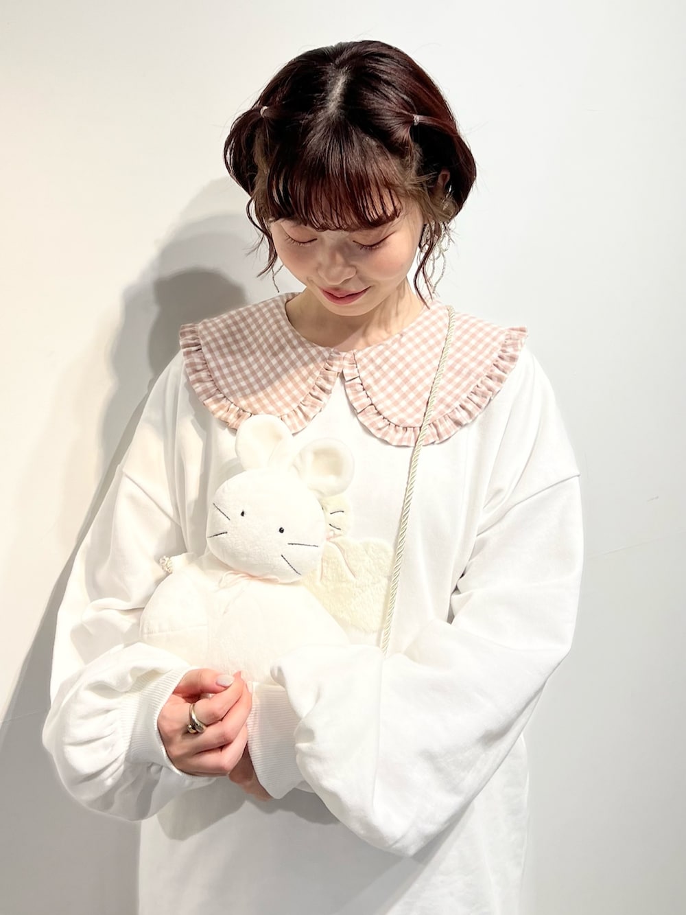 ホワイト系のショルダーバッグ、ピンク系のワンピース、ホワイト系のスウェットを着用したレディースの冬コーディネートの6枚目の写真