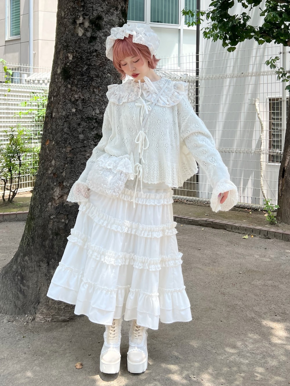 ホワイト系のハンドバッグ、ホワイト系のスカート、ホワイト系のブーツを着用したレディースの夏コーディネートの2枚目の写真