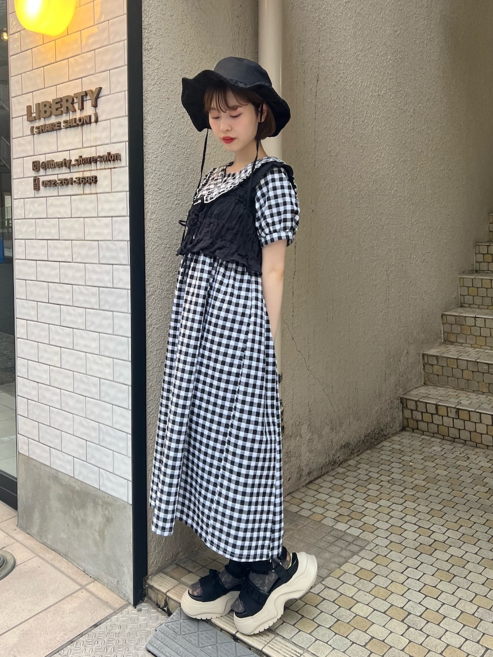 ブラック系のベスト、ブラック系のサンダル、ブラック系のワンピースを着用したレディースの夏コーディネートの2枚目の写真