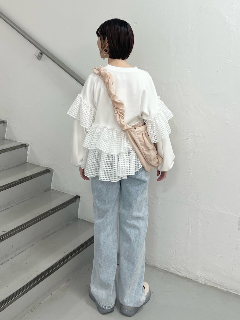 ホワイト系のスウェット、ブルー系のデニムパンツ、ホワイト系のスニーカーを着用したレディースの春コーディネートの3枚目の写真