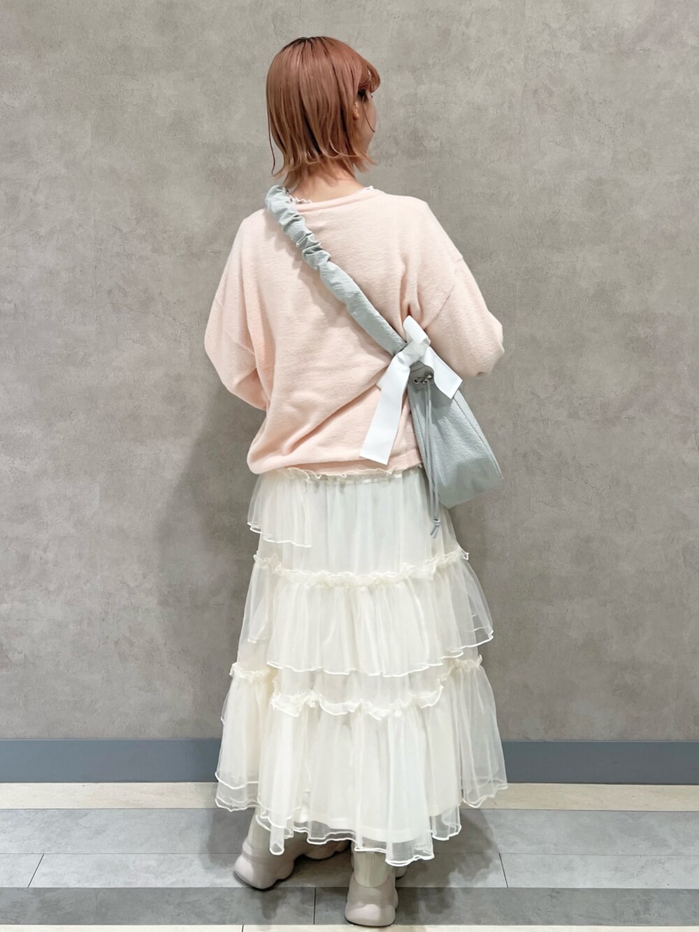 ピンク系のTシャツ/カットソー、ホワイト系のスカート、ホワイト系のスニーカーを着用したレディースの秋コーディネートの6枚目の写真