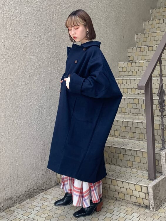 ブルー系のチェスターコート、ホワイト系のニット/セーター、レッド系のスカートを着用したレディースの秋コーディネートの5枚目の写真