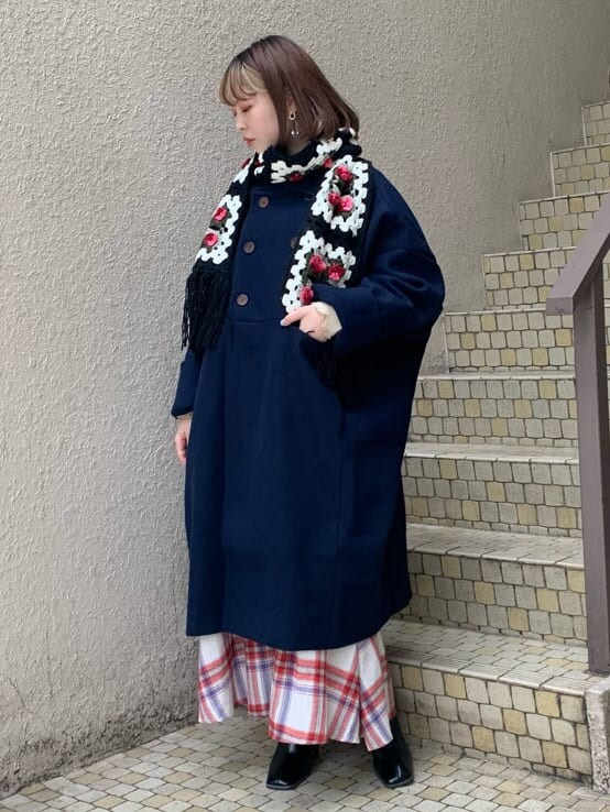 ブルー系のチェスターコート、ホワイト系のニット/セーター、レッド系のスカートを着用したレディースの秋コーディネートの3枚目の写真