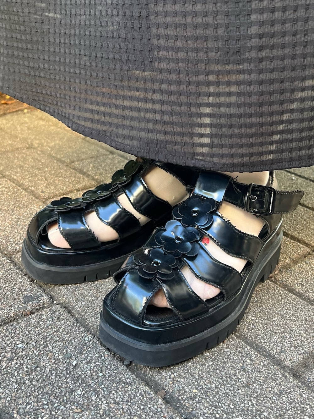 ブラック系のハンドバッグ、ブラック系のワンピース、ブラック系のサンダルを着用したレディースの春コーディネートの7枚目の写真