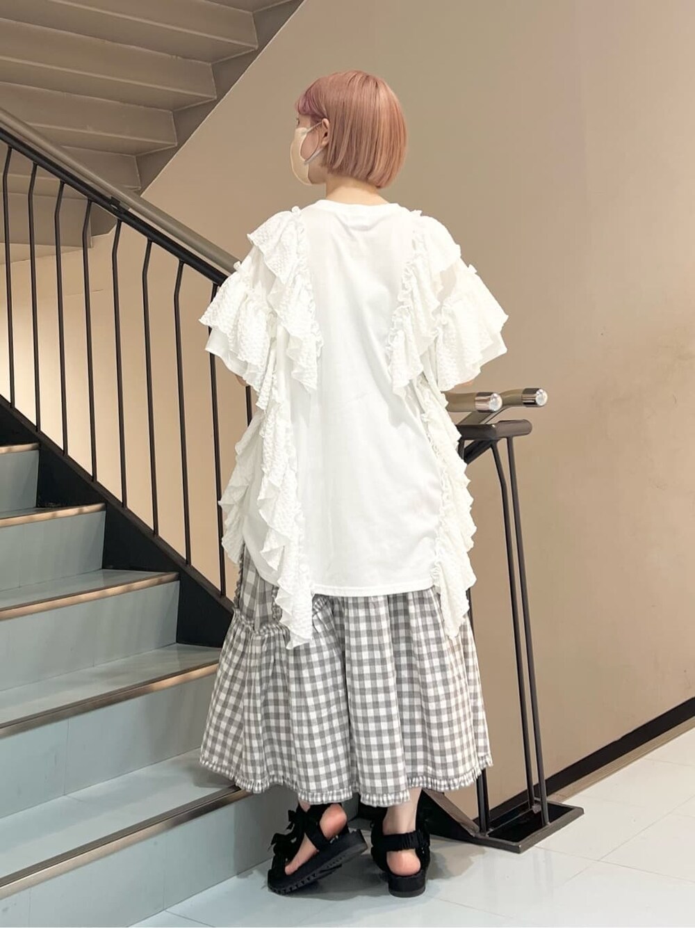 ホワイト系のチュニック、グレー系のスカート、ブラック系のサンダルを着用したレディースの夏コーディネートの2枚目の写真