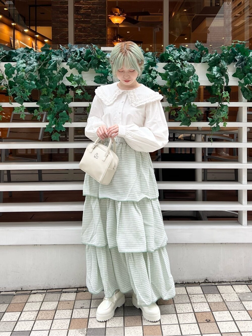 ホワイト系のシャツ/ブラウス、グリーン系のスカート、ホワイト系のボストンバッグを着用したレディースの秋コーディネートの2枚目の写真