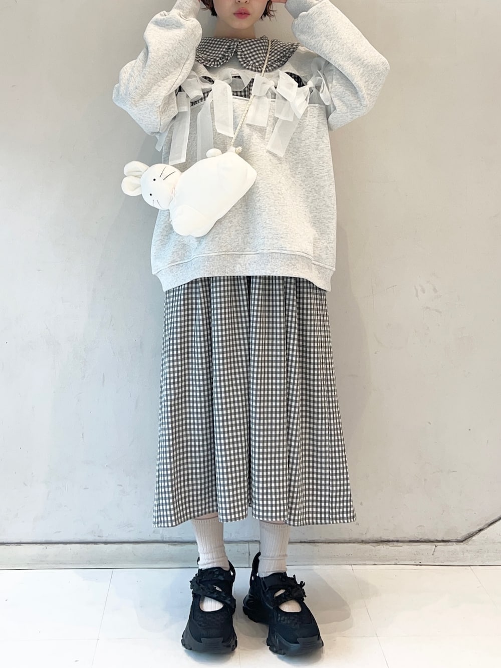 ブラック系のワンピース、ブラック系のスニーカー、ホワイト系のショルダーバッグを着用したレディースの冬コーディネートの3枚目の写真