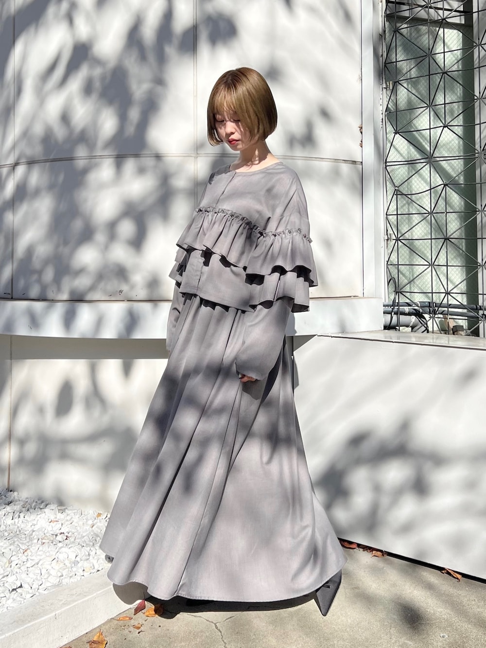 グレー系のテーラードジャケット、グレー系のスカート、ブラック系のパンプスを着用したレディースの秋コーディネートの3枚目の写真