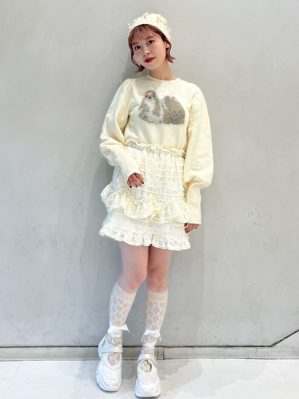 ホワイト系のノーカラーコート、ホワイト系のスカート、ホワイト系のニット/セーターを着用したレディースの冬コーディネートの9枚目の写真