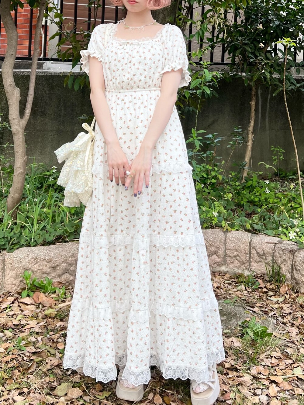 ホワイト系のワンピース、ホワイト系のショルダーバッグ、ベージュ系のサンダルを着用したレディースの春コーディネートの3枚目の写真