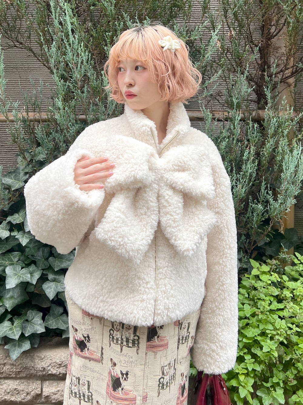 ホワイト系のブルゾン、ベージュ系のジャンパースカート、レッド系のハンドバッグを着用したレディースの秋コーディネートの4枚目の写真