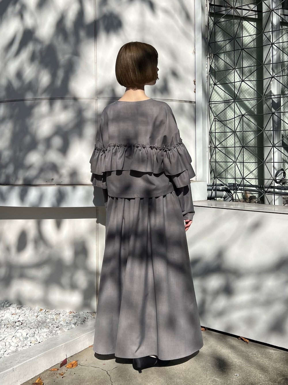 グレー系のテーラードジャケット、グレー系のスカート、ブラック系のパンプスを着用したレディースの秋コーディネートの5枚目の写真