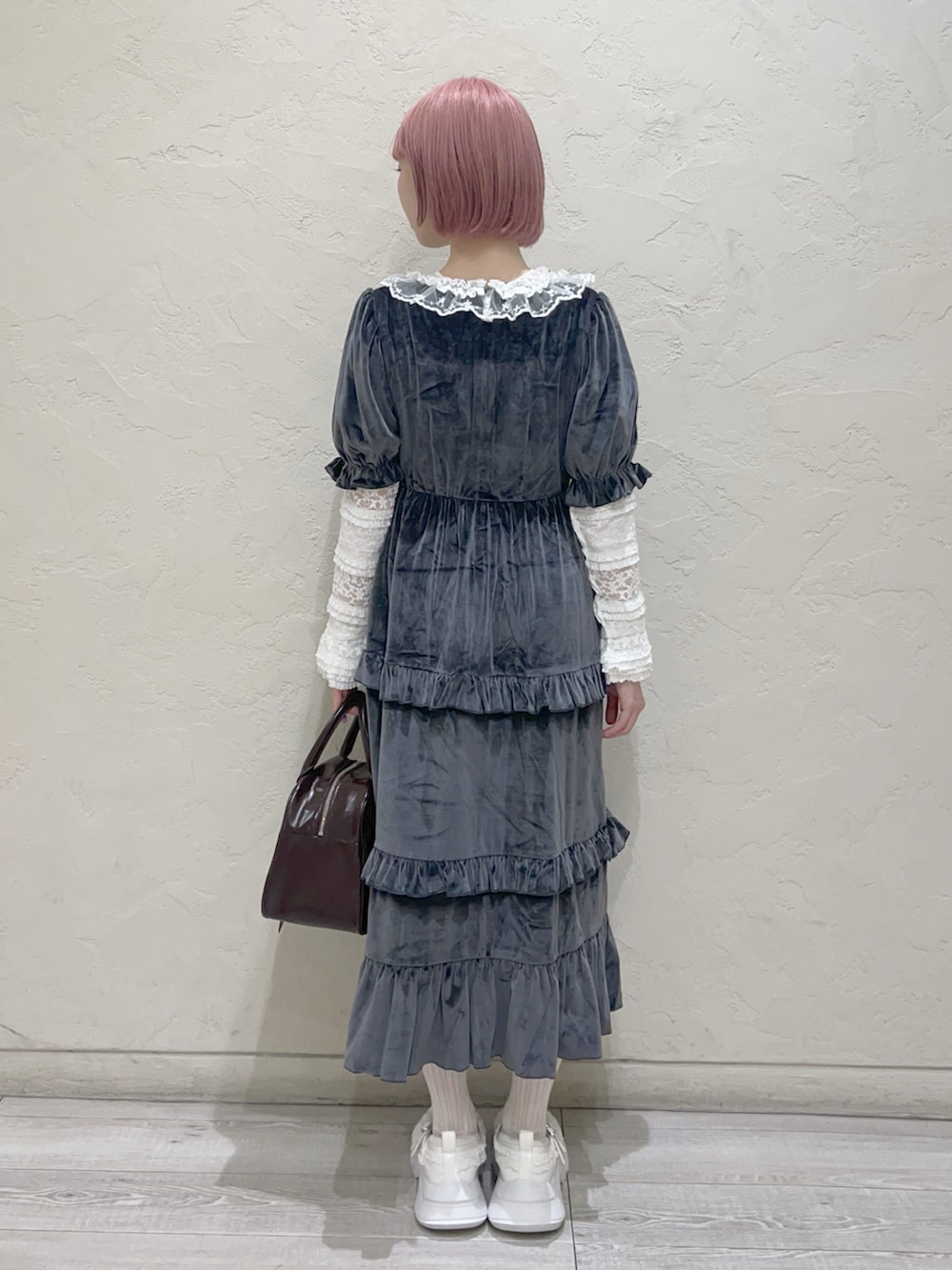 グレー系のワンピース、ブラウン系のハンドバッグ、ホワイト系のスニーカーを着用したレディースの夏コーディネートの4枚目の写真